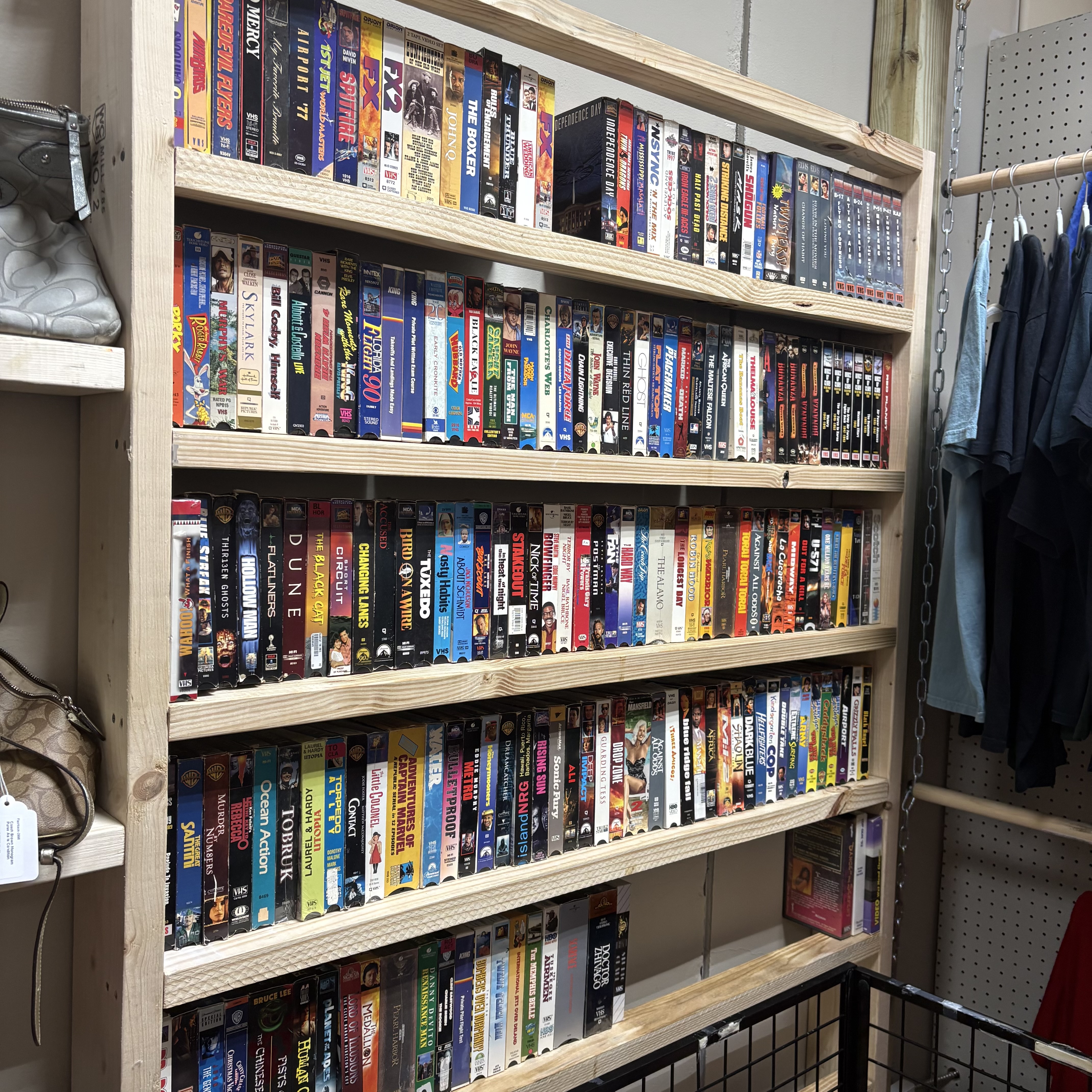 VHS tapes and boxed media on wooden shelves